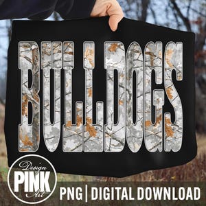 May include: Black digital design featuring the word "BULLDOGS" in large, white, block letters. The letters are filled with a camouflage pattern of grey, white, and brown. The design includes the text "Design PINK Art" and "PNG | DIGITAL DOWNLOAD".