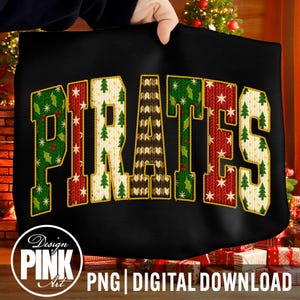 May include: Black tote bag with the word "PIRATES" in a festive, Christmas-themed design. The letters are filled with patterns of Christmas trees, snowflakes, and knitted textures in green, red, and cream colors. The bag is held up by a person's hands.