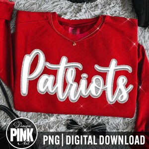 May include: A bright red long-sleeve sweatshirt featuring the word Patriots in a large, white, three-dimensional script font with a silver glitter outline. The garment has a crew neckline and a visible interior tag at the collar area.