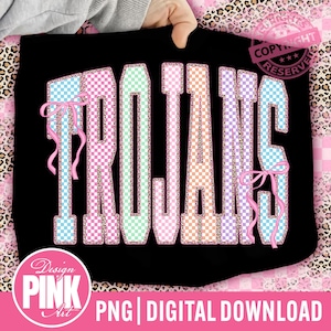 Könnte beinhalten: Schwarzes T-Shirt mit dem Wort "TROJANS" in einem farbenfrohen, karierten Design. Die Buchstaben sind in verschiedenen Pastellfarben umrandet, mit rosa Schleifen. Das Design enthält den Text "Design PINK Art" und "PNG DIGITAL DOWNLOAD".