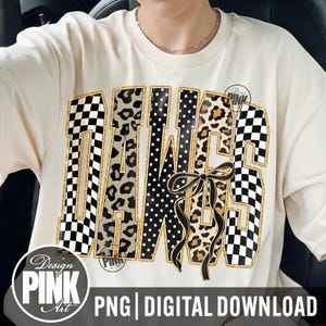 May include: Cream-colored t-shirt with a large graphic design. The design spells out "DAWGS" in a mix of patterns: checkered, leopard print, and polka dots, with a black bow. The shirt also has the text "Design PINK Art" and "PNG | DIGITAL DOWNLOAD".