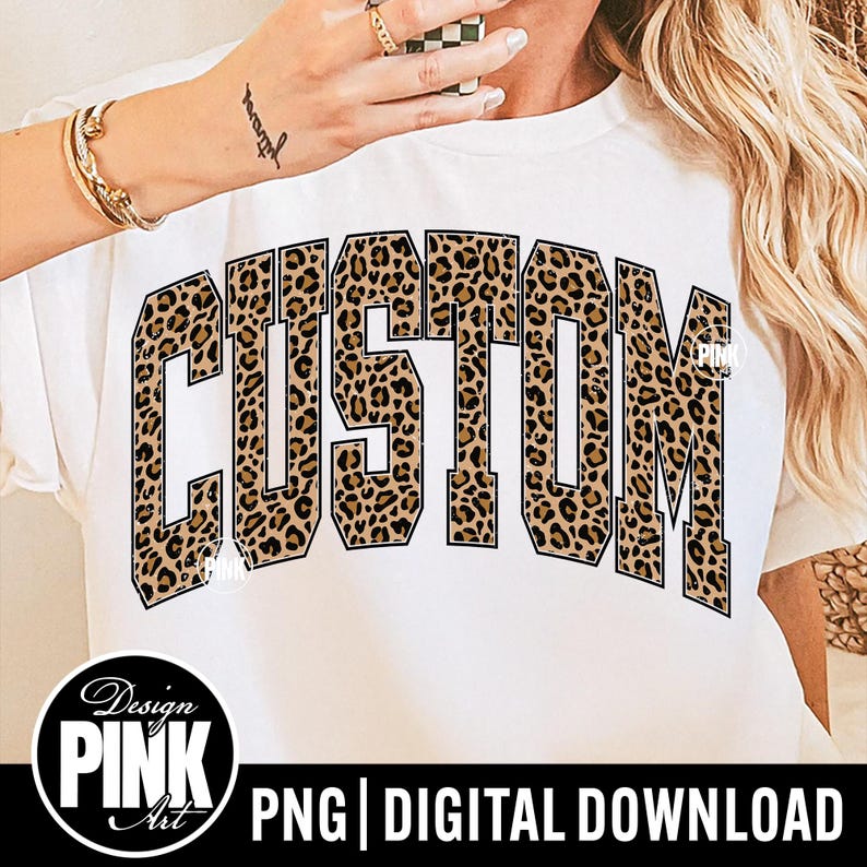 May include: White t-shirt featuring the word "CUSTOM" in a leopard print pattern. The shirt has a crew neck and short sleeves. The design includes the text "Design PINK Art" and "PNG | DIGITAL DOWNLOAD".
