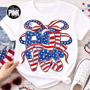 Peut inclure: T-shirt blanc avec un motif patriotique "4th of July" en rouge, blanc et bleu. Le texte est stylisé avec un ruban et des étoiles. Le t-shirt a un col rond et des manches courtes.