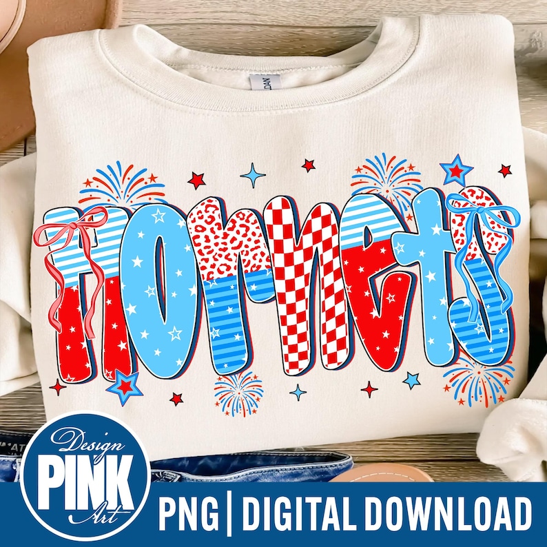 May include: Cream-colored sweatshirt with the word "HORNETS" in a colorful, patriotic design. The letters feature red, white, and blue patterns, including stripes, checks, and animal print, with star and firework accents.