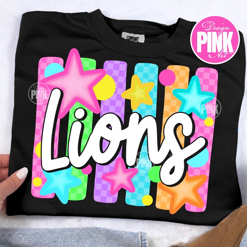 May include: Black sweatshirt with the word "Lions" in white script, decorated with colorful stars and vertical stripes in pink, green, orange, and purple. The design includes a pink circle with the text "Design PINK Art".