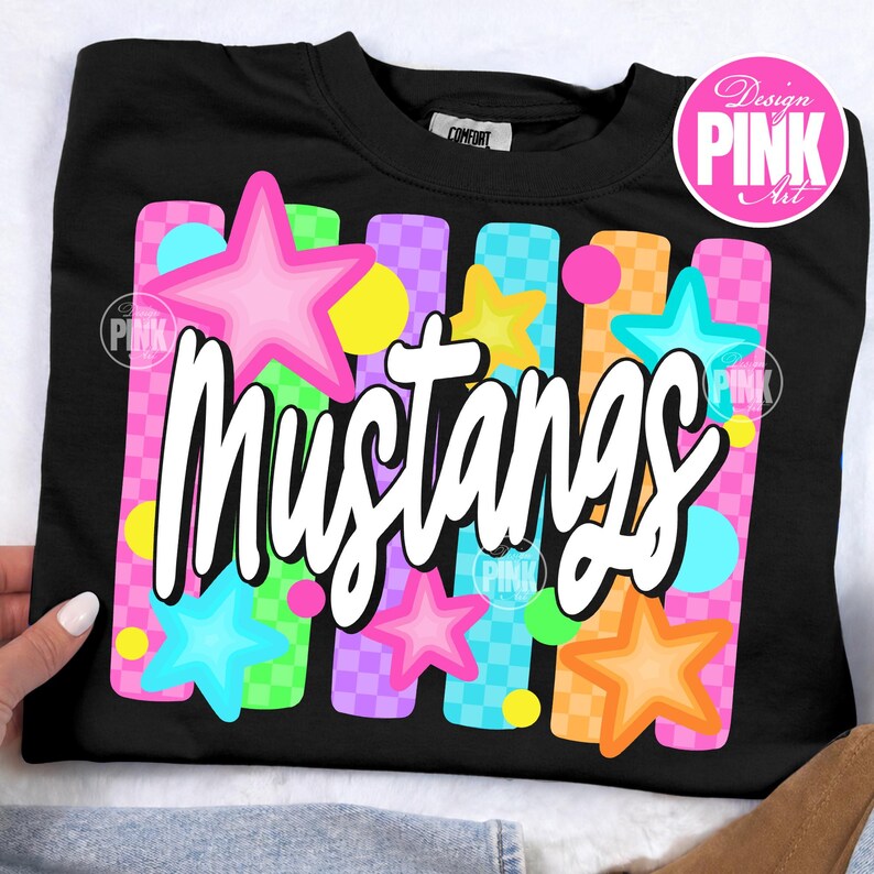 May include: Black sweatshirt with the word "Mustangs" in white script. The design includes colorful stars and vertical stripes in pink, blue, yellow, and orange. The sweatshirt has a crew neck.