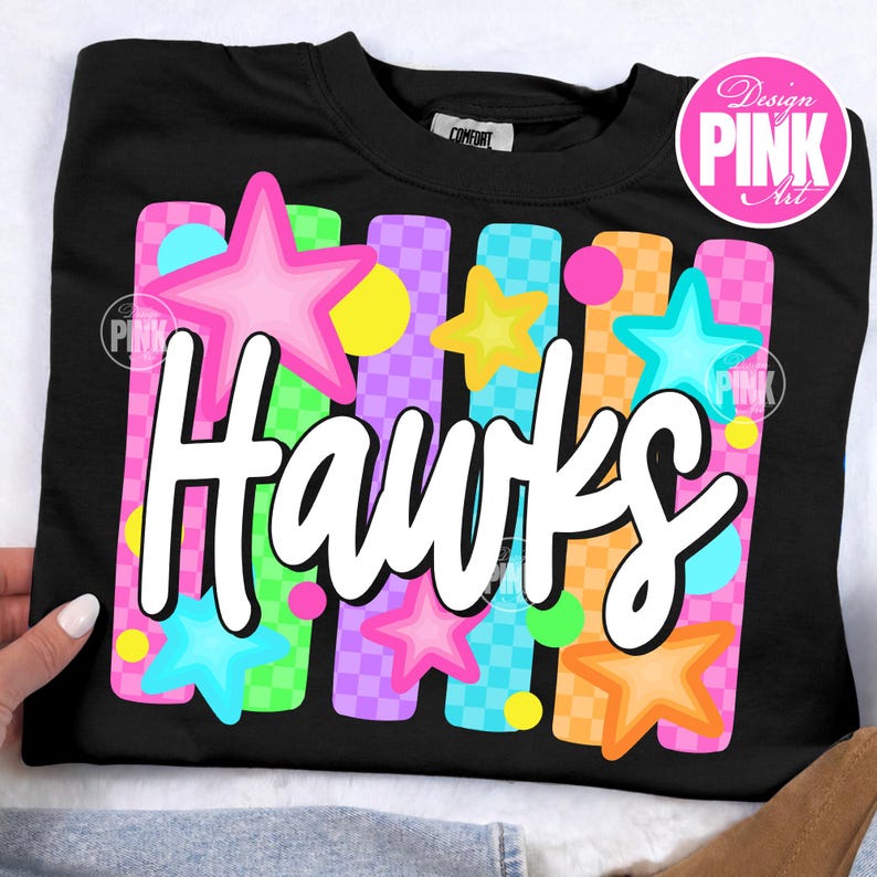 May include: Black sweatshirt with the word "Hawks" in white script. The design includes colorful stars and vertical stripes in pink, orange, green, and purple. The sweatshirt has a crew neck and a tag that says "Comfort".