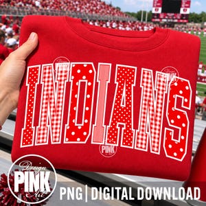 Könnte beinhalten: Ein leuchtend rotes Sweatshirt mit Rundhalsausschnitt und dem Wort INDIANS in großen, fettgedruckten, weiß umrandeten Blockbuchstaben. Die Buchstaben sind mit abwechselnden Mustern aus weißen Punkten, rot-weißem Vichy-Karo und vertikalen Streifen gefüllt.