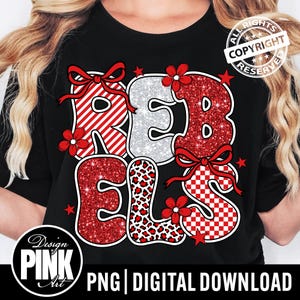 May include: Black t-shirt with the word "REBELS" in a mix of patterns and textures. The letters are red glitter, white and red stripes, leopard print, and red and white checkered. Red bows and flowers accent the letters.