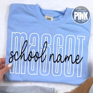 K&ouml;nnte beinhalten: Hellblaues Sweatshirt mit dem Wort "MASCOT" in wei&szlig;en Blockbuchstaben und "school name" in schwarzer Schreibschrift. Das Sweatshirt hat ein "Design Pink Art" Logo in der oberen rechten Ecke.