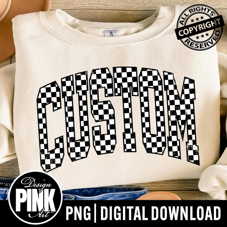 May include: A cream-colored crewneck sweatshirt featuring the word CUSTOM printed in a black and white checkered pattern across the chest. The text is arched in a collegiate font style. A circular black copyright badge is visible in the top right.