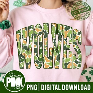 Peut inclure: Sweat-shirt rose avec le mot "WOLVES" en grandes lettres de style camouflage. Le texte est un mélange de vert, de marron et d'orange. Le design comprend un tampon de copyright et le texte "PNG | TÉLÉCHARGEMENT NUMÉRIQUE".