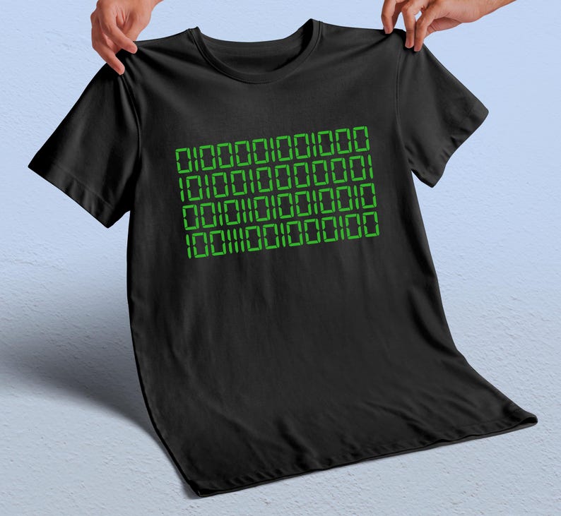 May include: Black t-shirt with a green binary code design. The binary code is arranged in four rows of numbers. The t-shirt is made of a soft material.