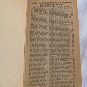 May include: An open book with German text, featuring a list of hymns and religious texts. The pages are aged, with a worn appearance, and the text is in black ink.