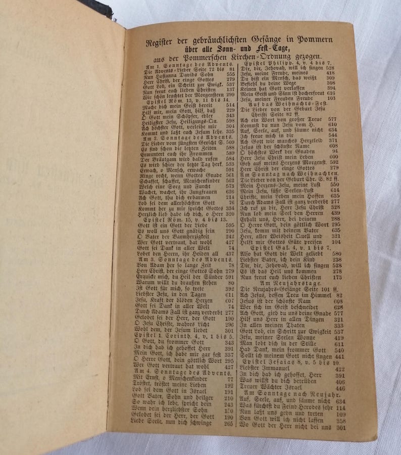 May include: An open book with German text, featuring a list of hymns and religious texts. The pages are aged, with a worn appearance, and the text is in black ink.