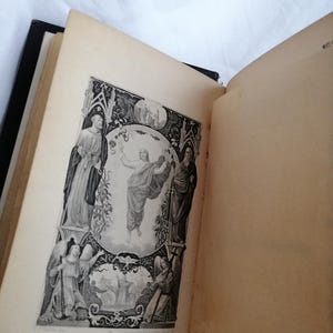 May include: An open antique book with a black spine, displaying a detailed black and white illustration. The illustration depicts figures in religious attire, with text in German below the image. The pages are aged with a yellowed hue.