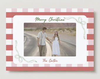 May include: A Christmas-themed photo frame with a red and white gingham border. The frame has a white interior with a photo of a couple walking on a road. The words "Merry Christmas" and "The Carters" are written on the frame.