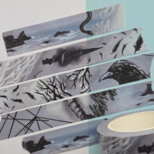 May include: Decorative washi tape roll with a gray and white design. The tape features illustrations of a snake, crow, feathers, and a seascape. The tape is partially unrolled, revealing the design. The background is white and light blue.