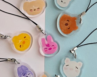 May include: A collection of clear acrylic charms featuring various cartoon animal faces, including a dog, bunny, bear, and cat. Each charm is attached to a black lanyard with a silver-colored clasp. The charms are in shades of yellow, pink, orange, purple, and white.