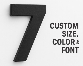 May include: A black metal number seven house number mounted on a white wall. The number has a modern, angular design. Text on the right reads "CUSTOM SIZE, COLOR & FONT".