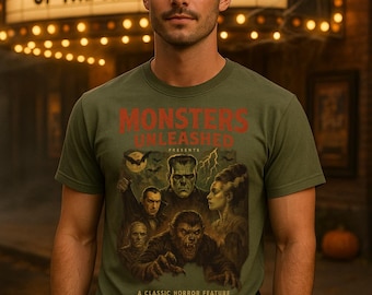 May include: Olive green t-shirt with a classic horror movie poster design featuring Frankenstein's monster, the Wolfman, and other iconic monsters. The text "MONSTERS UNLEASHED" is displayed in red. The background includes a vintage movie theater marquee.