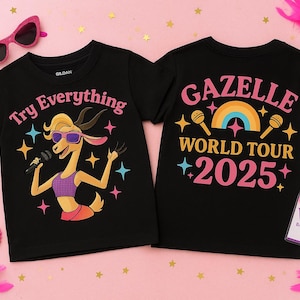 Könnte beinhalten: Schwarze T-Shirts mit einer Cartoon-Gazelle, die eine Sonnenbrille trägt und ein Mikrofon hält. Auf der Vorderseite steht "Try Everything". Auf der Rückseite steht "Gazelle World Tour 2025". Zubehör: rosa Sonnenbrille, Armbänder und VIP-Abzeichen.