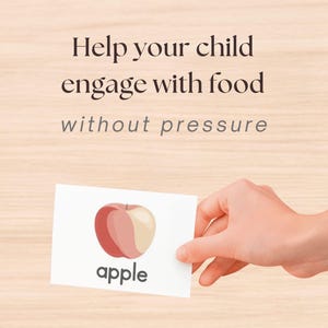 May include: A hand holding a white card with a red and beige apple illustration and the word "apple" below it. The card is against a light wood grain background. Text at the top reads "Help your child engage with food without pressure."
