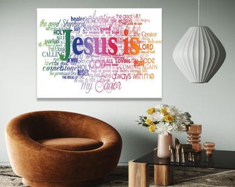 Puede incluir: Una obra de arte enmarcada con las palabras "Jesus is" en texto colorido, rodeada de palabras relacionadas como "Salvador", "Señor" y "Esperanza". La obra de arte se exhibe en un salón moderno con un sillón marrón y una mesa de centro negra.