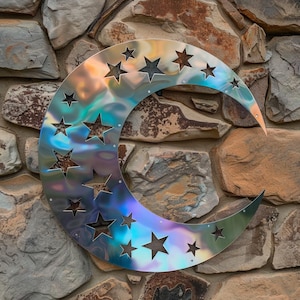 May include: A crescent moon-shaped metal wall art piece with star cutouts. The metal has a reflective, iridescent finish with hues of silver, blue, and purple. The art is mounted on a textured stone wall, creating a striking contrast.