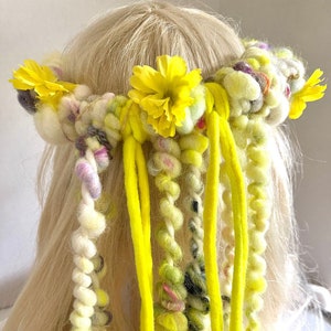 May include: A yellow yarn hair crown with yellow flowers and long yellow yarn strands hanging down.