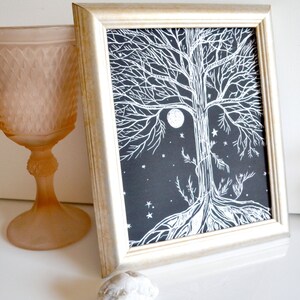 Puede incluir: Una impresi&oacute;n enmarcada en blanco y negro de un &aacute;rbol con una luna llena y estrellas en el fondo. El &aacute;rbol est&aacute; estilizado con intrincadas ramas y ra&iacute;ces.