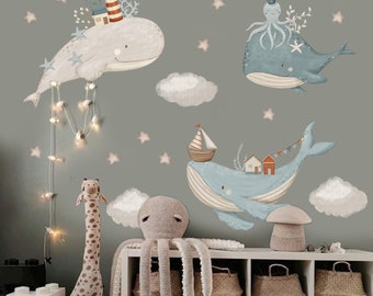 Peut inclure: Une chambre d'enfant avec un mur vert clair décoré d'autocollants muraux de baleines et de poulpes. Les autocollants sont dans des tons de bleu et de gris. Il y a aussi des nuages blancs et des étoiles sur le mur. La pièce a un tapis blanc, une boîte à jouets en bois et une girafe en peluche.