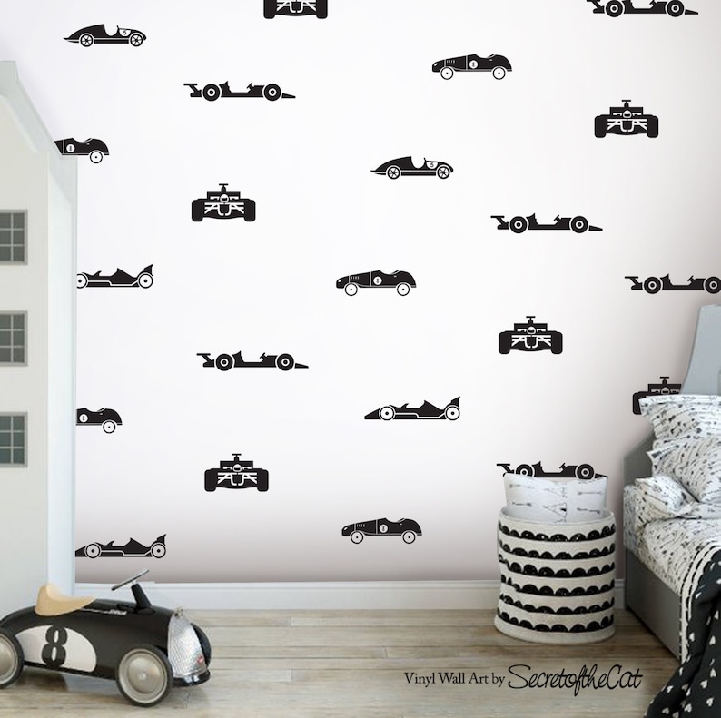 Peut inclure: Un ensemble d'autocollants muraux en vinyle noir repr&eacute;sentant diverses silhouettes de voitures de course, incluant des styles de Formule 1 anciens et modernes, dispos&eacute;s sur un mur blanc. Le texte Vinyl Wall Art by SecretoftheCat est imprim&eacute; en noir.