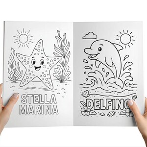 Może przedstawiać: Kolorowanka otwarta na dw&oacute;ch stronach, trzymana w dłoniach. Jedna strona przedstawia uśmiechniętą rozgwiazdę z napisem "STELLA MARINA". Druga strona przedstawia delfina wyskakującego z wody z napisem "DELFINO".