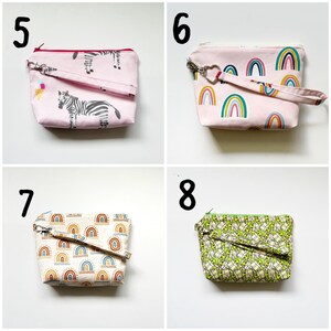 Pu&ograve; includere: Quattro pochette rosa con cerniera con diversi motivi. Le pochette hanno un cinturino da polso e sono realizzate in tessuto. I motivi includono zebre, arcobaleni e un motivo verde.