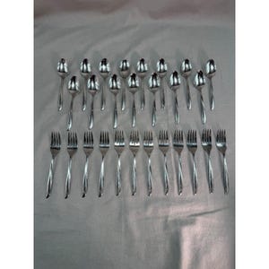 May include: A collection of twenty-seven stainless steel utensils arranged in two rows. The top row consists of fourteen spoons, and the bottom row consists of thirteen forks. Each piece features a polished silver finish and a simple, smooth handle design.