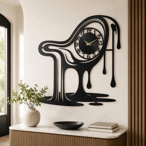 May include: A black wall clock with a fluid, melting design that drips toward the bottom. The circular clock face features black numerals and thin gold hands. The overall structure is abstract, resembling liquid spilling down a flat surface.