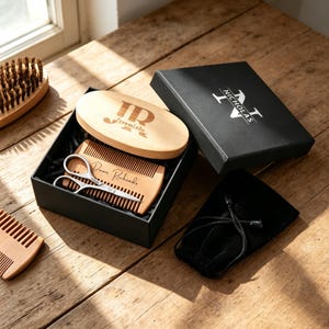 May include: A wooden beard grooming kit presented in a black box. The kit contains a wooden brush, comb, scissors, and a small black bag. The box is branded with the name "Nicholas". The comb is engraved with the name "Dave Richards".