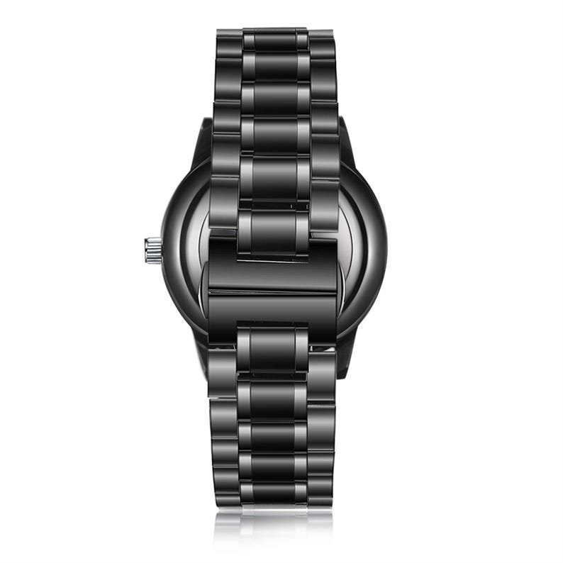 May include: A black wristwatch with a stainless steel strap. The watch face is round and dark, with a matching black strap. The watch has a classic design and a polished finish.