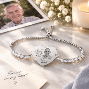 Op de afbeelding: Een verstelbare zilverkleurige armband met een hartvormige bedel gegraveerd met een portret van een oudere man, de tekst "I Am Always With You" en de naam "William". De armband is bezet met heldere, fonkelende steentjes langs de band.