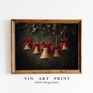 May include: A framed vintage print featuring five golden bells adorned with red bows, suspended from a garland of evergreen branches, holly, and berries. The artwork has a dark, moody background and the text "VIN ART PRINT" and "Subtle Vintage Stories".
