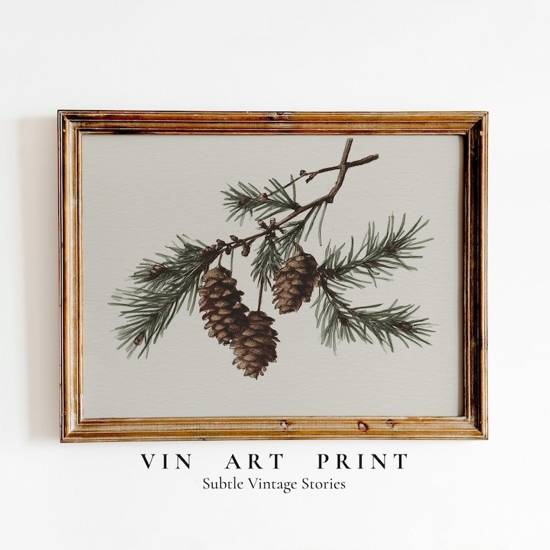 May include: A framed art print featuring a watercolor illustration of pine cones and evergreen branches. The artwork has a vintage aesthetic, with a neutral background and a warm-toned wooden frame. The text "VIN ART PRINT" and "Subtle Vintage Stories" are at the bottom.