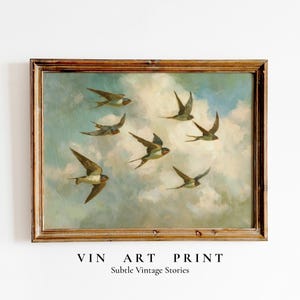 Op de afbeelding: Vintage kunstprint met zwaluwen die door een bewolkte lucht vliegen, omlijst door een bruine houten lijst. De print bevat de tekst "VIN ART PRINT" en "Subtle Vintage Stories" aan de onderkant.