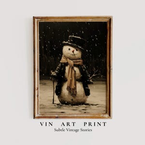 Puede incluir: Una impresión artística vintage enmarcada de un muñeco de nieve en una escena nevada. El muñeco de nieve lleva un sombrero de copa negro, un abrigo y una bufanda marrón. La impresión tiene un tono sepia y el texto "VIN ART PRINT" y "Subtle Vintage Stories".