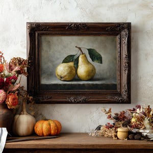 May include: A framed oil painting depicting two yellow pears with green leaves resting on a flat surface. The artwork is enclosed in a dark brown, ornate, carved wooden frame with intricate floral and scrollwork details along the edges.
