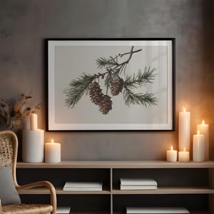 May include: A framed print featuring a detailed illustration of a pine branch with green needles and brown pine cones. The artwork is displayed above a wooden shelf with white candles, creating a cozy, nature-inspired aesthetic.