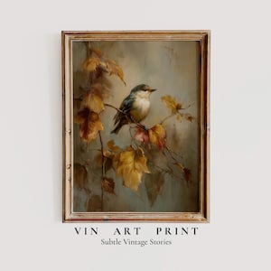 Può includere: Stampa artistica incorniciata in stile vintage con un piccolo uccello appollaiato su un ramo con foglie autunnali. L'opera d'arte ha una tavolozza di colori tenui con toni oro, marrone e blu. Il testo in basso recita "VIN ART PRINT" e "Subtle Vintage Stories."
