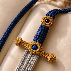 May include: A handcrafted crochet sword in shades of blue, gold, and gray. The hilt and crossguard are gold, with a blue gem in the center. The handle is blue, and the blade is gray. The sword is made of yarn.