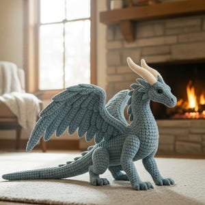 May include: A crocheted dragon in shades of blue, with large wings, horns, and a long tail. The dragon is posed on a rug in front of a fireplace. The dragon is a handmade item.