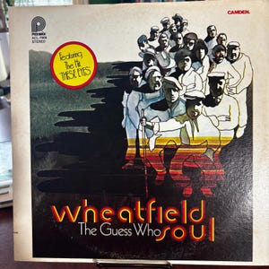 May include: Vintage vinyl record album cover for "Wheatfield" by The Guess Who. The cover features a group illustration of people in various outfits. The album title is in yellow and red text. The text "Featuring The Hit THESE EYES" is in a yellow circle.